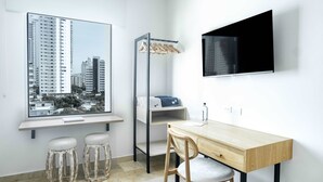 A modern room with a large window, a bed with a wooden frame, a desk with a chair, and a TV mounted on the wall. - w Startling Loft in the Heart of Bocagrande (Cartagena)
