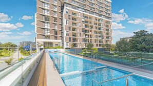 Un moderno edificio residencial de varios pisos con piscina en la azotea.