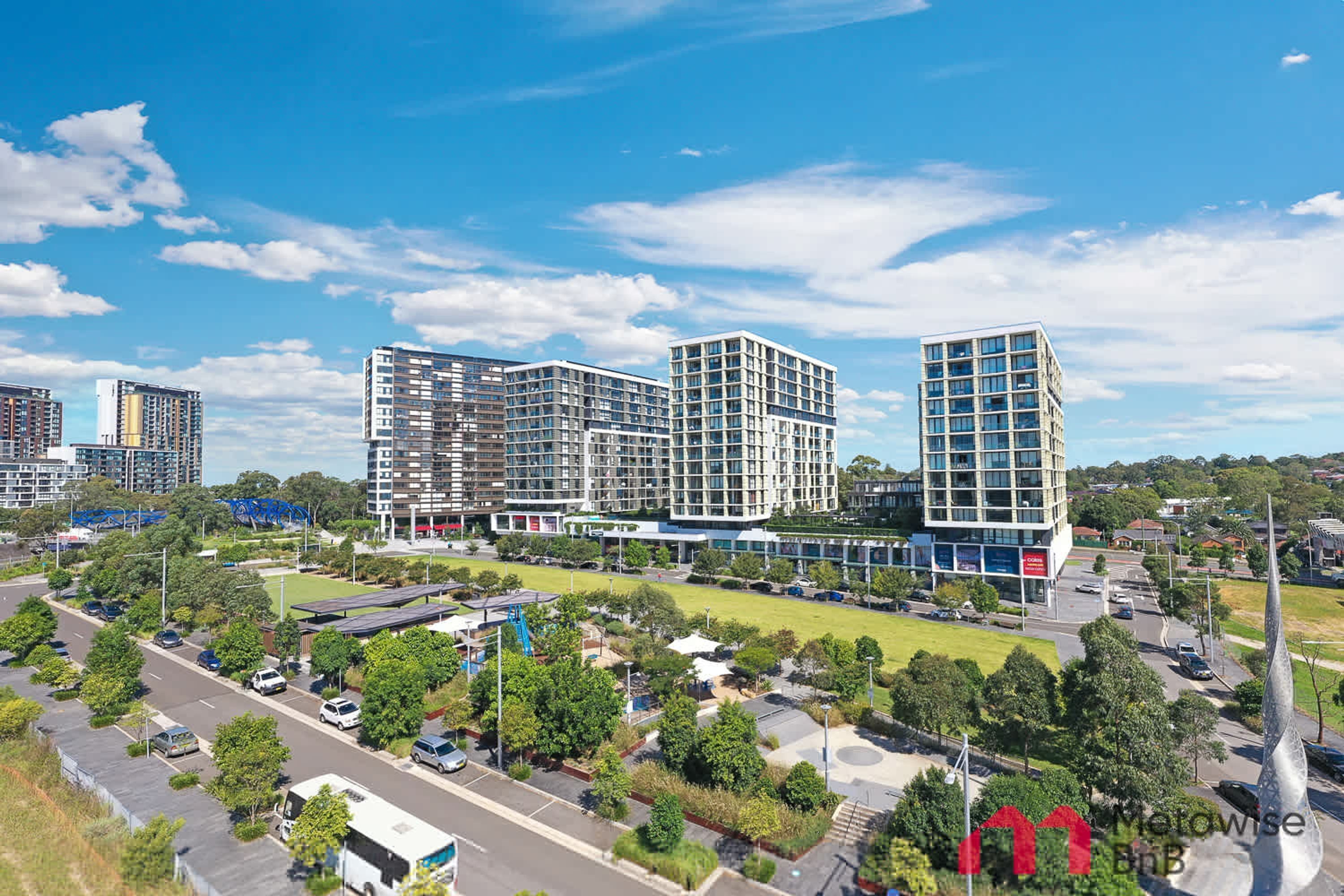 A modern urban area with multi-story buildings, a parking lot, and green spaces.