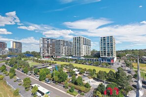 Una zona urbana moderna con edificios de varios pisos, un estacionamiento y áreas verdes.