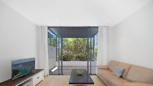 Una sala de estar moderna con un sofá, una mesa de centro y un televisor sobre un mueble de madera.