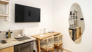 A compact kitchen with a built-in dishwasher, a dining area with two wicker chairs, and a large mirror reflecting the kitchen. - w Spotless Loft in the Heart of Bocagrande (Cartagena)