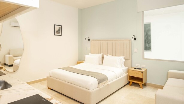 A modern bedroom with a large bed, bedside tables, a nightstand, and a view of the outdoors. - w Spotless Loft in the Heart of Bocagrande (Cartagena)