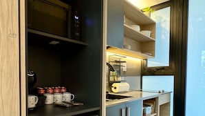 A modern kitchen with a built-in refrigerator, microwave, and coffee machine. There are shelves with kitchenware and a window providing natural light. - w Forest Escape Bungalow With Nature View (Caimitillo)