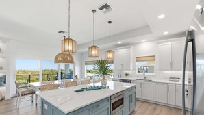 A modern kitchen with a large island, white cabinets, and pendant lighting. - Ocean Views Beach Optional Heated Pool Spa (Palm Coast)