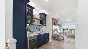 A modern kitchen with dark blue cabinets, a herringbone tile backsplash, and a built-in oven. - Ocean Views Beach Optional Heated Pool Spa (Palm Coast)