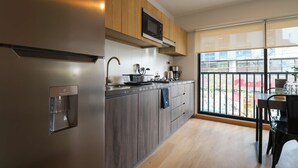 A modern kitchen with a built-in microwave, a water dispenser, and a large window overlooking a balcony. - w Graceful 1BR w/ Perfect Balcony in Miraflores (Lima)