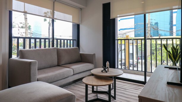 A modern living room with a sofa, a small round table, and large windows with a view of the city. - w Graceful 1BR w/ Perfect Balcony in Miraflores (Lima)