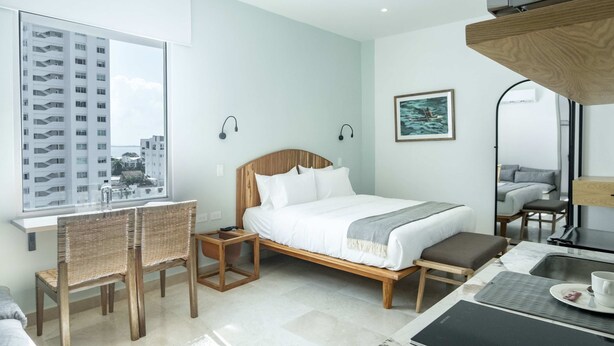 A modern hotel room with a large window, a bed, a desk with a chair, and a small table with a cup and saucer. - w Upscale Loft in the Heart of Bocagrande (Cartagena)