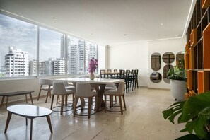 Ein moderner Essbereich mit großem Tisch und Stühlen, Blick auf die Stadt durch große Fenster und einer Wand mit dekorativen Spiegeln.