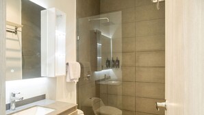 A modern bathroom with a large mirror, a sink, a toilet, and a glass-enclosed shower area. - w Inviting Loft in the Heart of Bocagrande (Cartagena)
