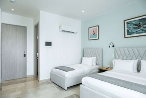 A modern hotel room with two single beds, a large bed, a headboard, a nightstand, an air conditioning unit, and a door. - w Inviting Loft in the Heart of Bocagrande (Cartagena)