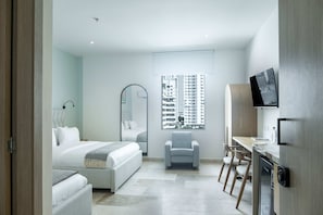 A modern hotel room with a bed, a desk, a chair, and a large window with a city view. - w Inviting Loft in the Heart of Bocagrande (Cartagena)