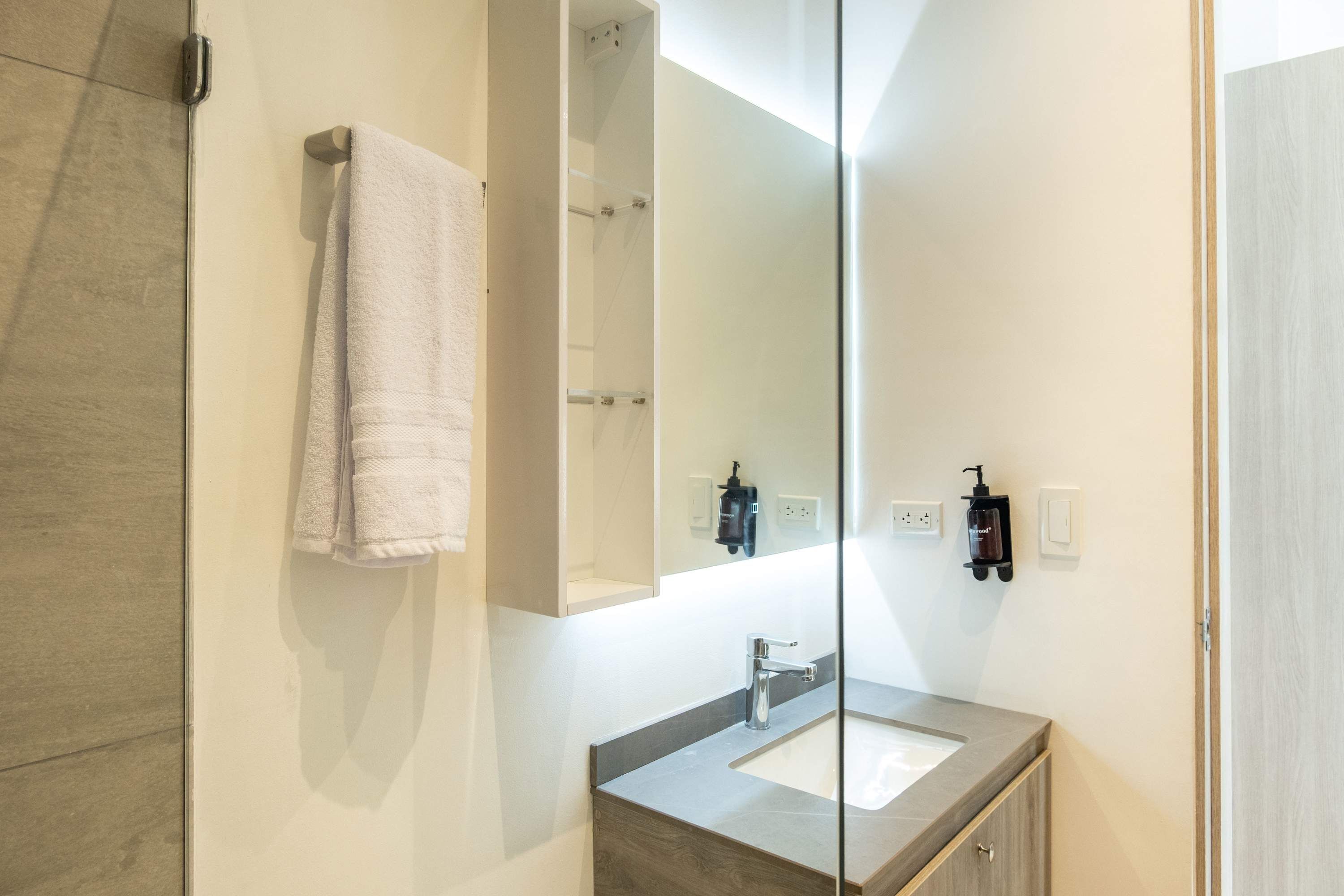 A modern bathroom with a large mirror, a sink, and a towel hanging on the wall.