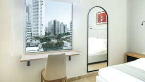 Ein modernes Schlafzimmer mit großem Fenster, einem Bett, einem Sessel und einem Spiegel.