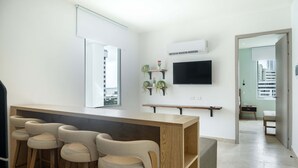 A modern kitchen with a bar area, a flat-screen TV, and a view of the city. - w Trendy 2BR in the Heart of Bocagrande (Cartagena)