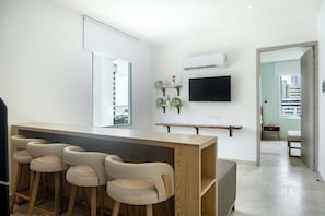 A modern kitchen with a bar area, a flat-screen TV, and a view of the city. - w Trendy 2BR in the Heart of Bocagrande (Cartagena)
