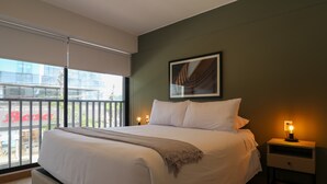 Een moderne slaapkamer met een groot bed, een nachtkastje met een lamp en een ingelijste foto aan de muur.