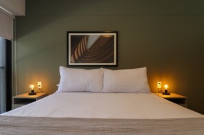 A neatly made bed with white linens, two bedside lamps, and a framed abstract artwork on the wall. - w Enchanting 2BR in the Heart of Miraflores (Lima)