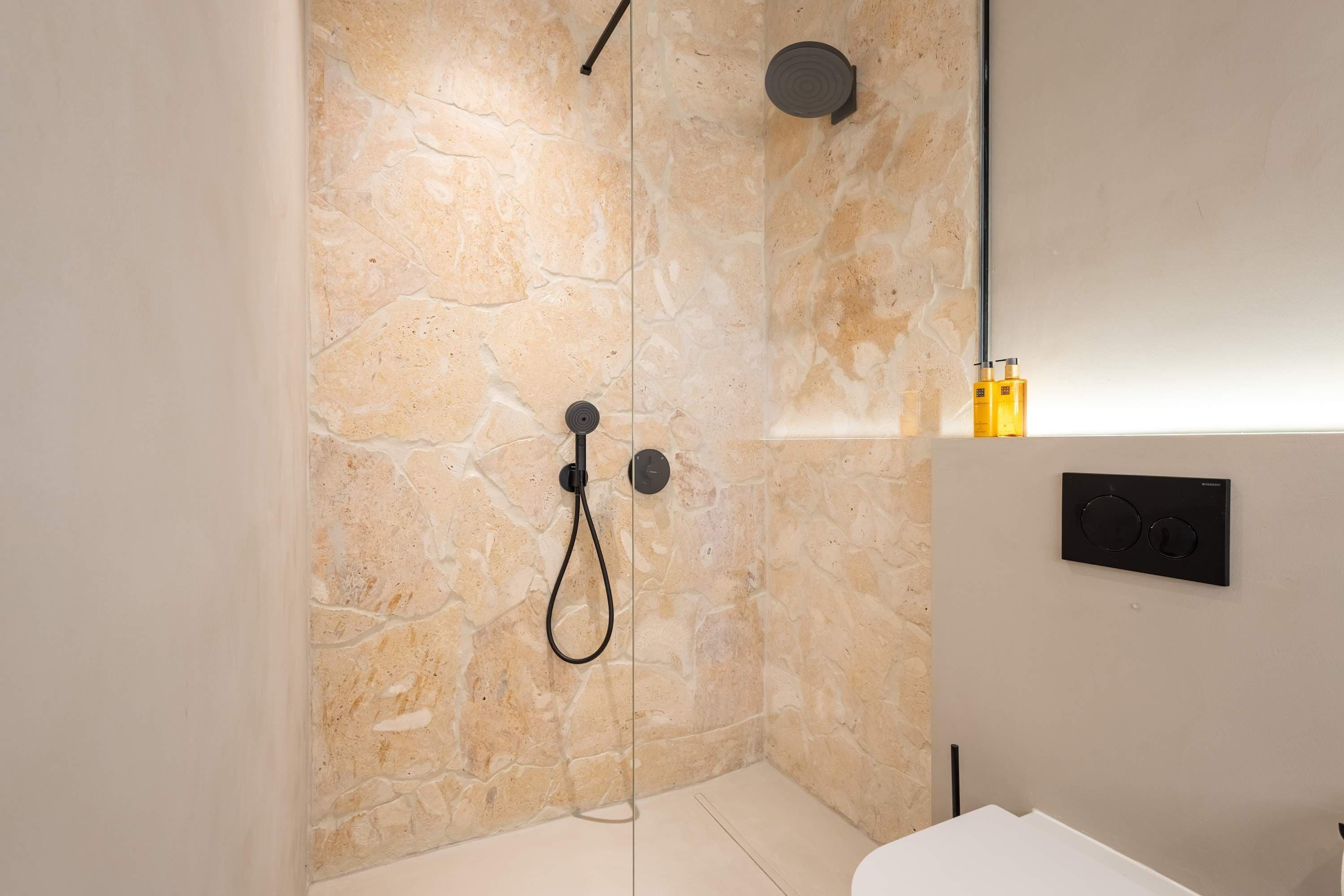 Un baño moderno con paredes de piedra, ducha y retrete.