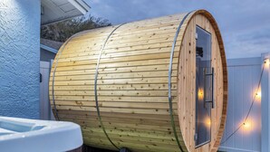 A wooden cylindrical structure with a glass door, possibly a hot tub or sauna, set on artificial grass with a white fence in the background. - Spacious 4-bedroom house with golf, Pool, Sauna, Jacuzzi & Firepit (Largo)