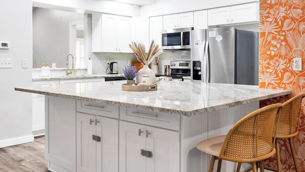 A modern kitchen with white cabinetry, a marble island, stainless steel appliances, and a decorative vase. - Spacious 4-bedroom house with golf, Pool, Sauna, Jacuzzi & Firepit (Largo)