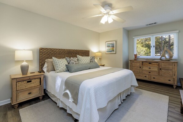 A bedroom with a bed, nightstands, a dresser, a ceiling fan, and a window with blinds. - 5 Pine Court: Pet Friendly Home in Sea Pines. 3 Beds, 2 Baths, Sleeps 7 (Hilton Head Island)