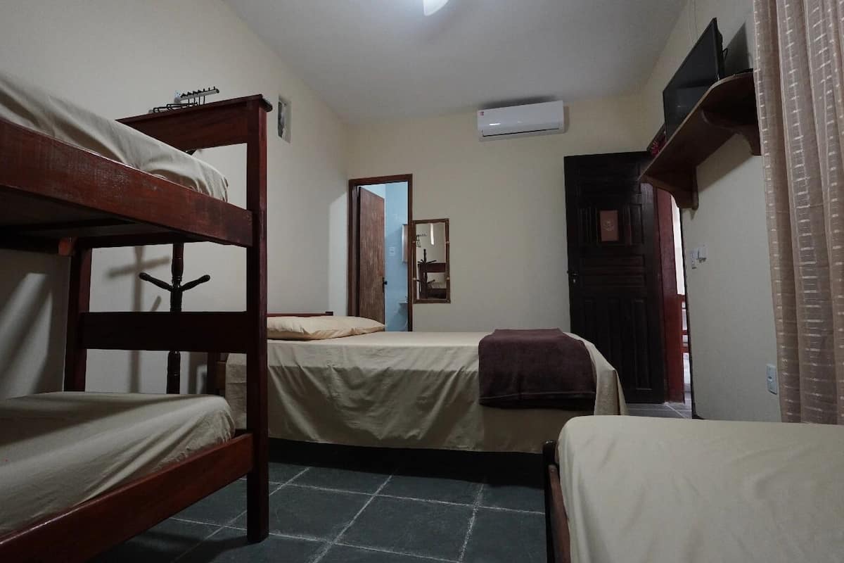 Un dormitorio con literas, una puerta, un equipo de aire acondicionado y una ventana con cortinas.