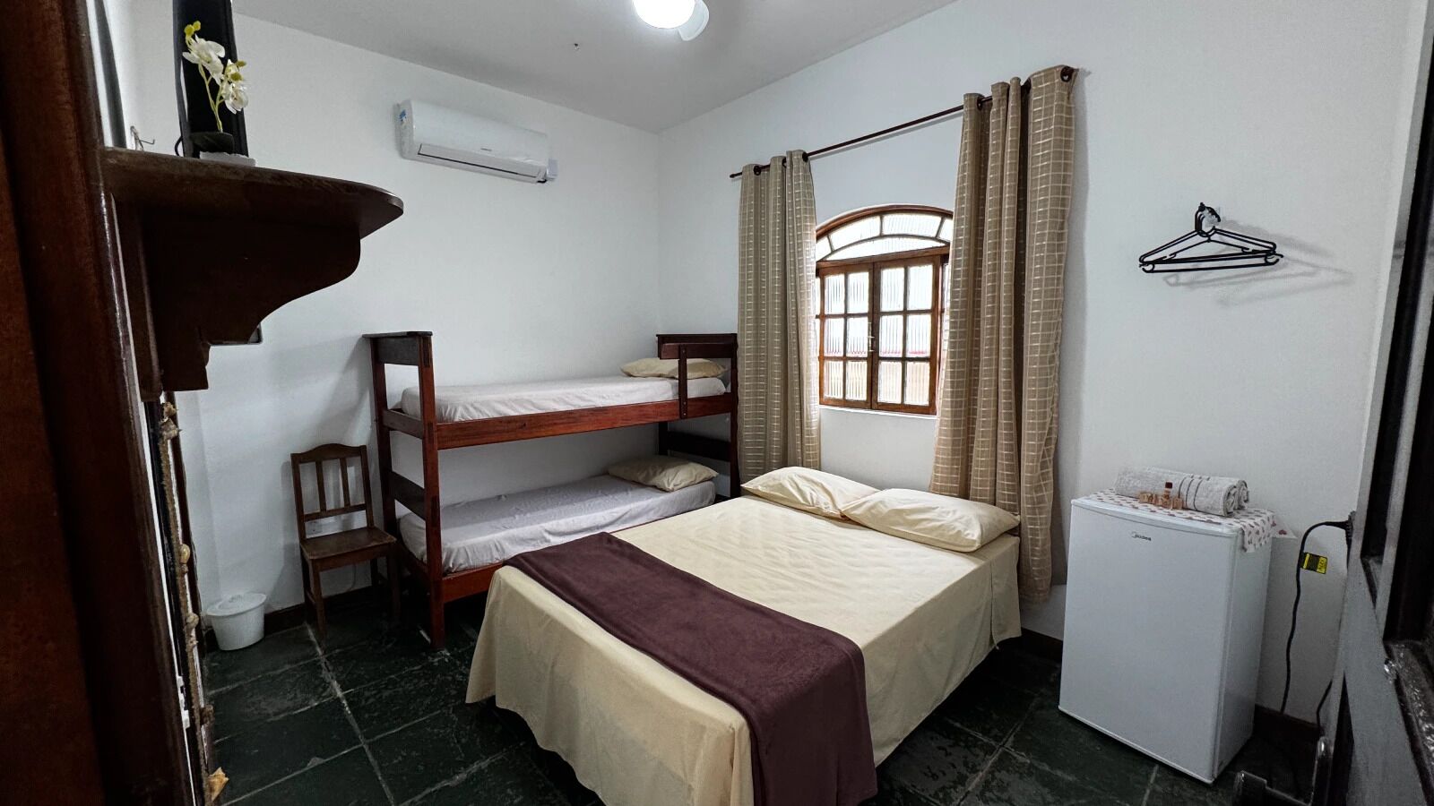 Una habitación pequeña con literas, un escritorio, un radiador y una ventana con cortinas.