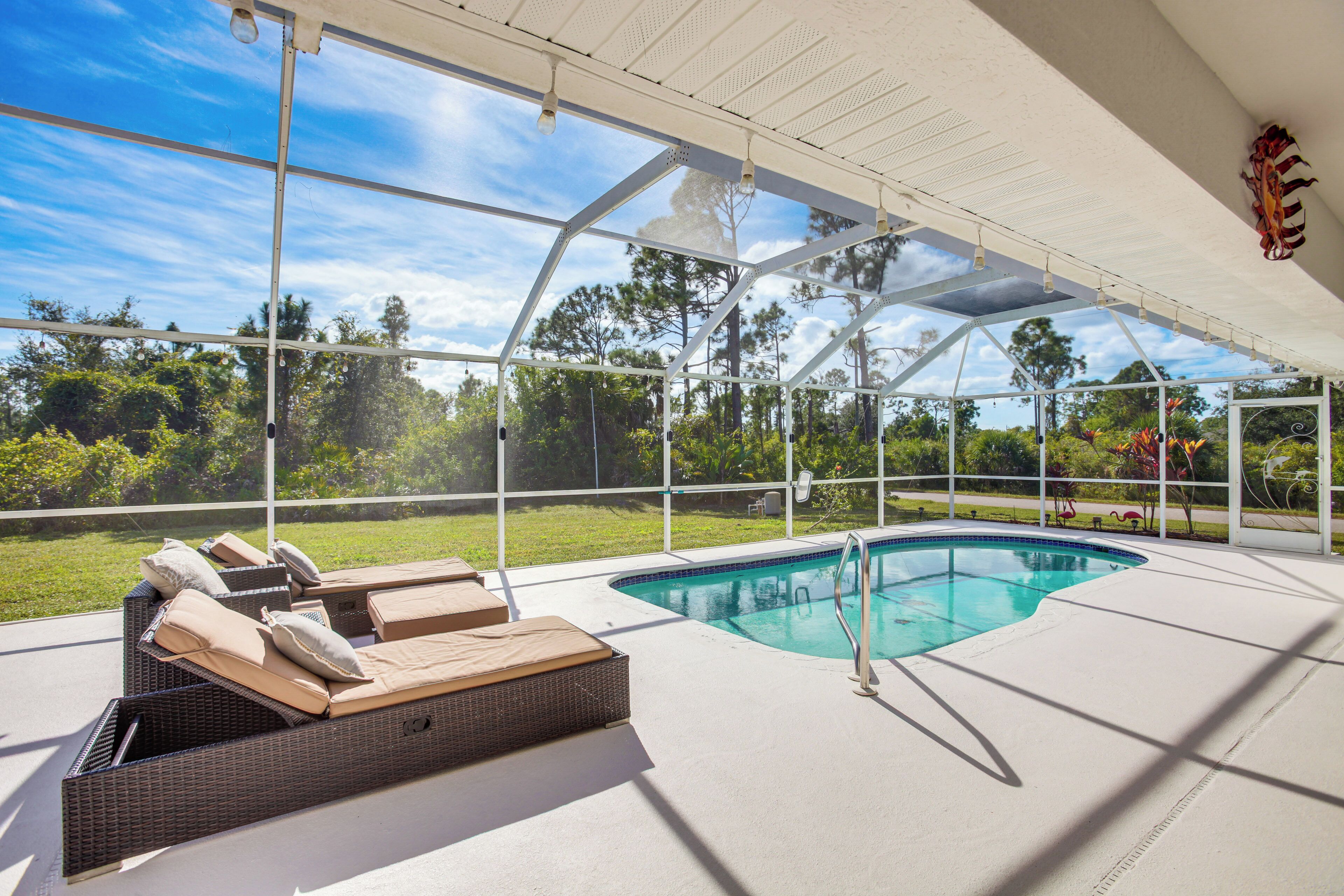 An indoor swimming pool area with lounge chairs and a glass ceiling.
