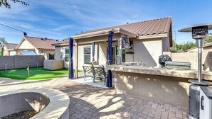 Un espace patio aménagé avec un barbecue, des sièges d’extérieur et une petite piscine.