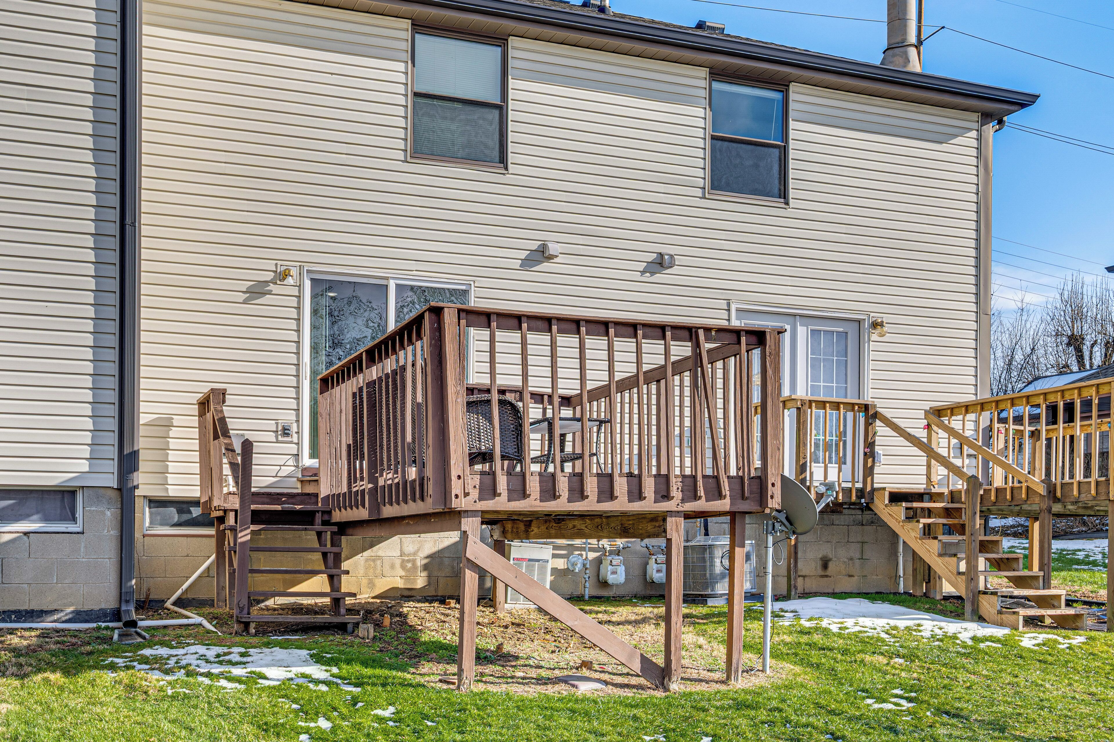 A two-story house with a wooden deck and stairs leading to the front door.