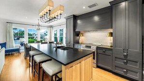 A modern kitchen with a large island, dark cabinetry, and a view of the outdoors. - Royal Harbor - Private Pool (Naples)