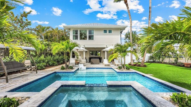 A pool with a house in the background, surrounded by palm trees and a well-maintained lawn. - Royal Harbor - Private Pool (Naples)