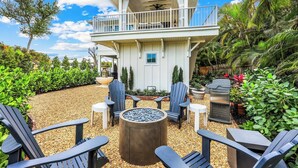 A two-story house with a balcony, outdoor seating area with Adirondack chairs, and a fire pit. - Royal Harbor - Private Pool (Naples)