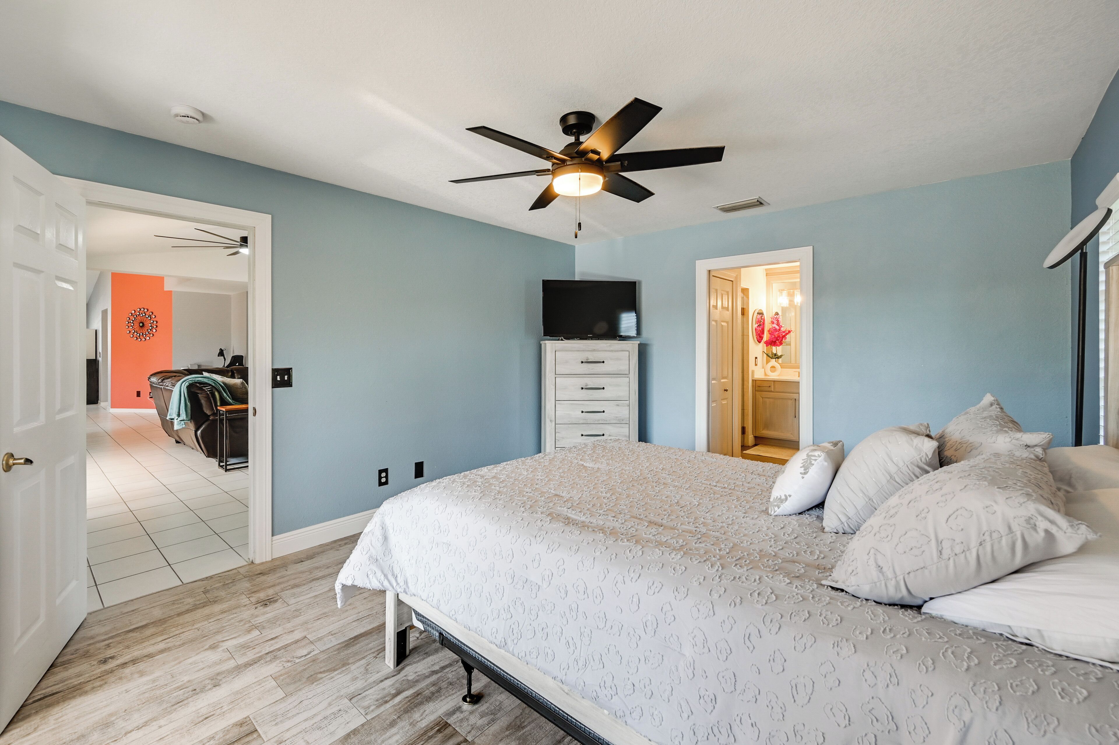 A bedroom with a bed, a ceiling fan, a TV, and a wardrobe.