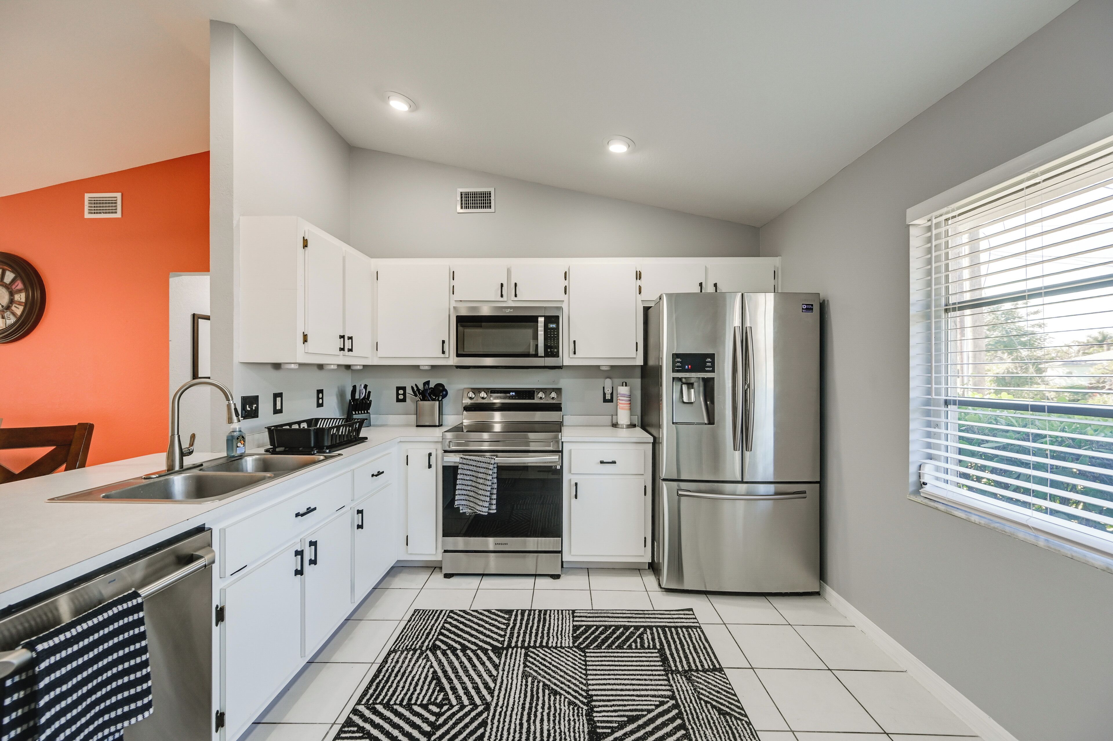 A modern kitchen with white cabinets, stainless steel appliances, a built-in oven, and a refrigerator.