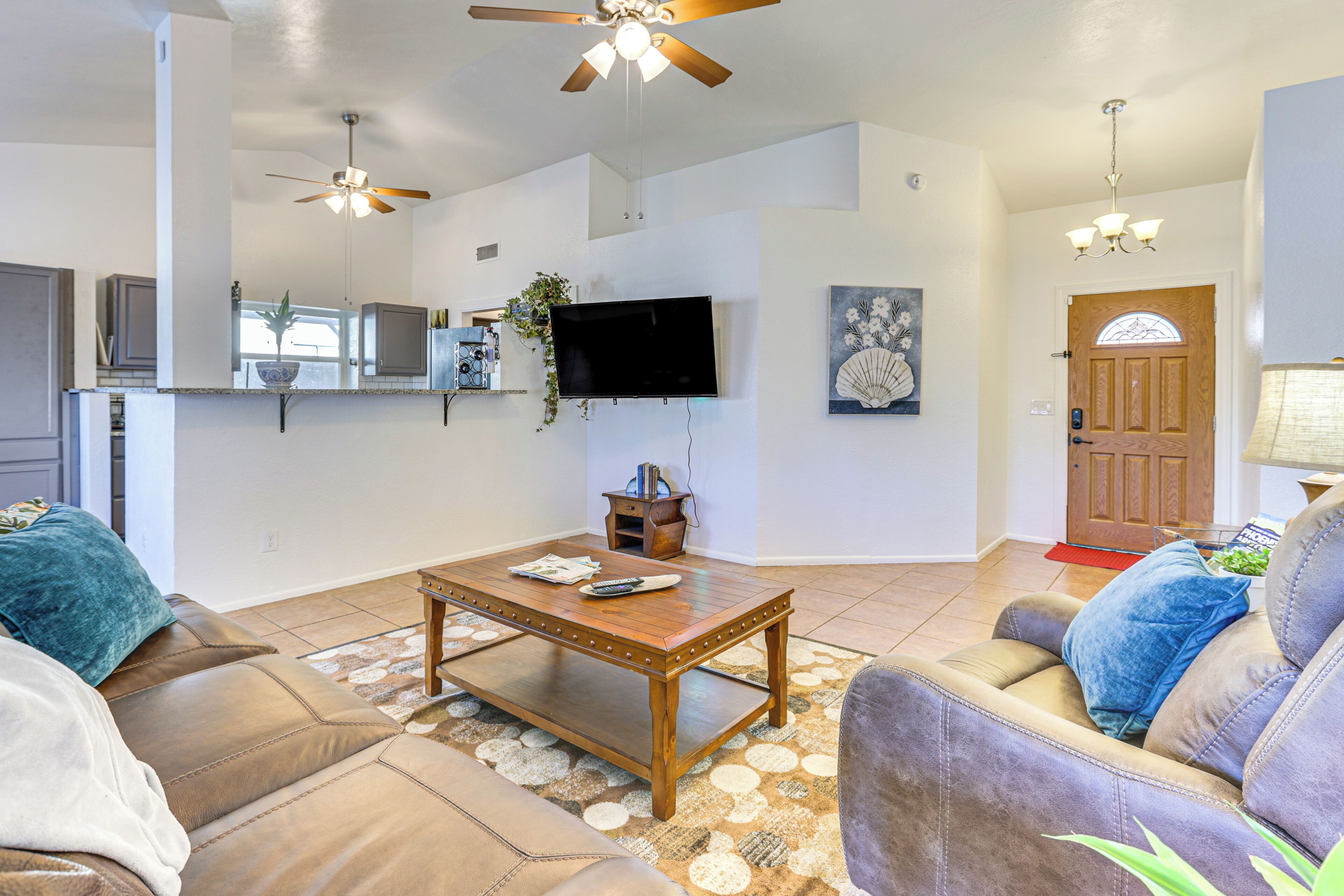 A spacious living room with a wooden coffee table, leather sofas, and a ceiling fan.