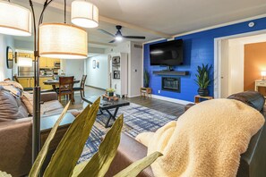 Ein modernes Wohnzimmer mit einer Couch, einem Couchtisch und einem an einer blauen Wand montierten Fernseher.