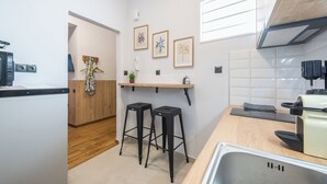 A compact kitchen with a wooden countertop, two stools, a sink, and a window with blinds. - Prime City Stay by Cloudkeys (Athens)
