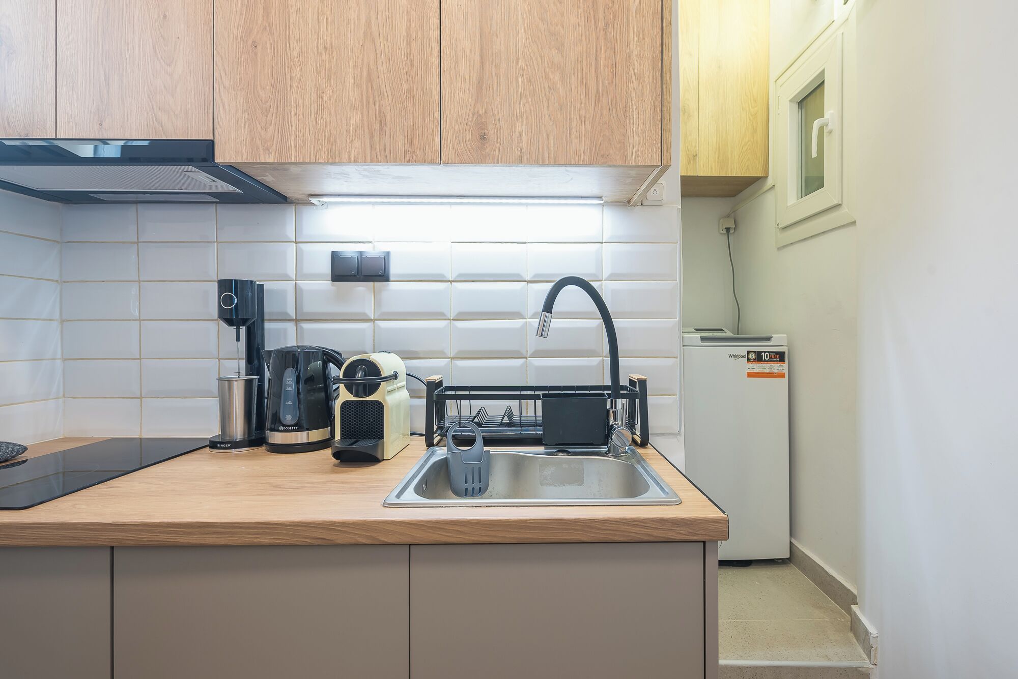 A kitchen with a sink, a coffee maker, a toaster, and a refrigerator.