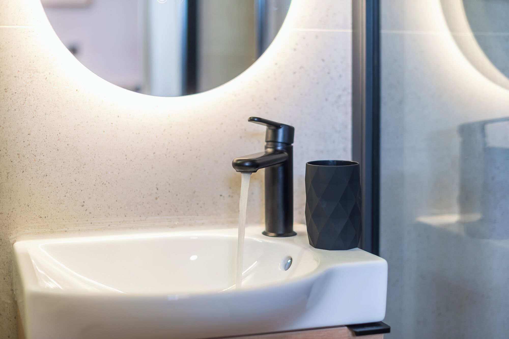 A bathroom sink with a faucet and a black mug.