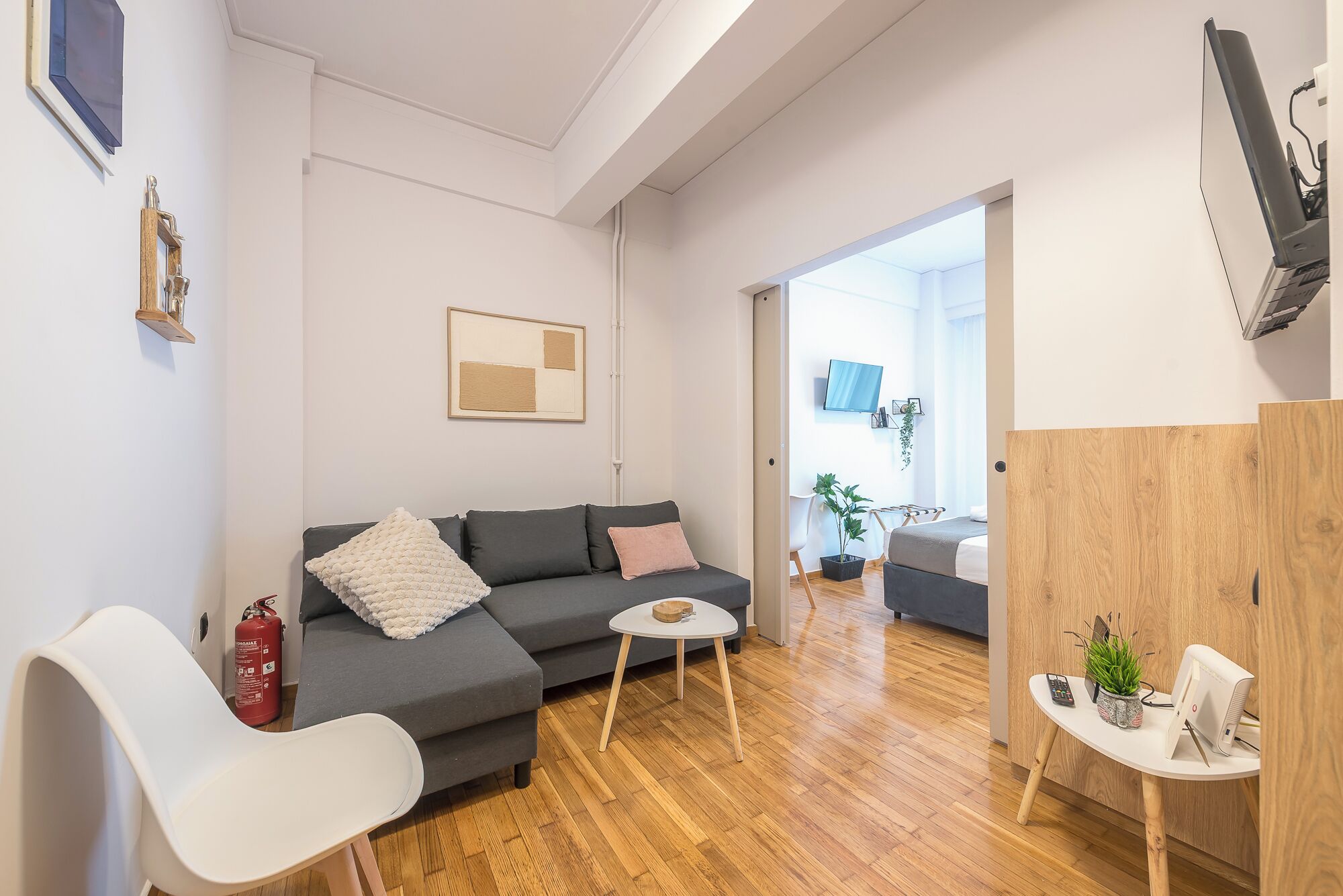 A modern living room with a grey sofa, a white chair, a small round table, and a wooden cabinet.