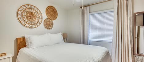 A bedroom with a large bed, a ceiling fan, and two wall decorations.