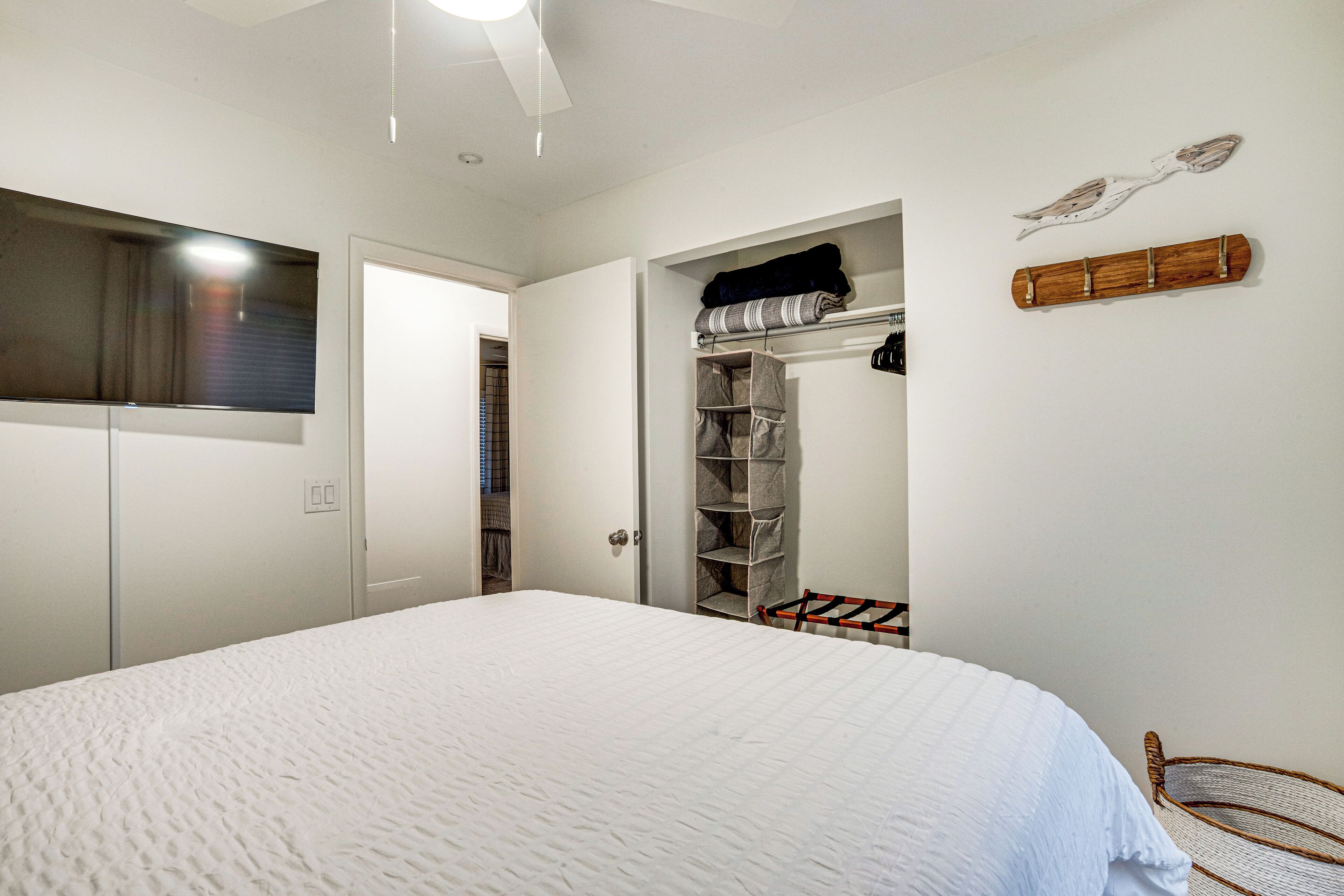 A bedroom with a bed, a wardrobe, a closet, and a hanging rack.