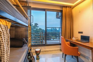 A room with a bunk bed, a desk with a laptop, a chair, and a view of trees through a large window. - The Hosteller Bam Dehradun, City Centre (Dehradun)