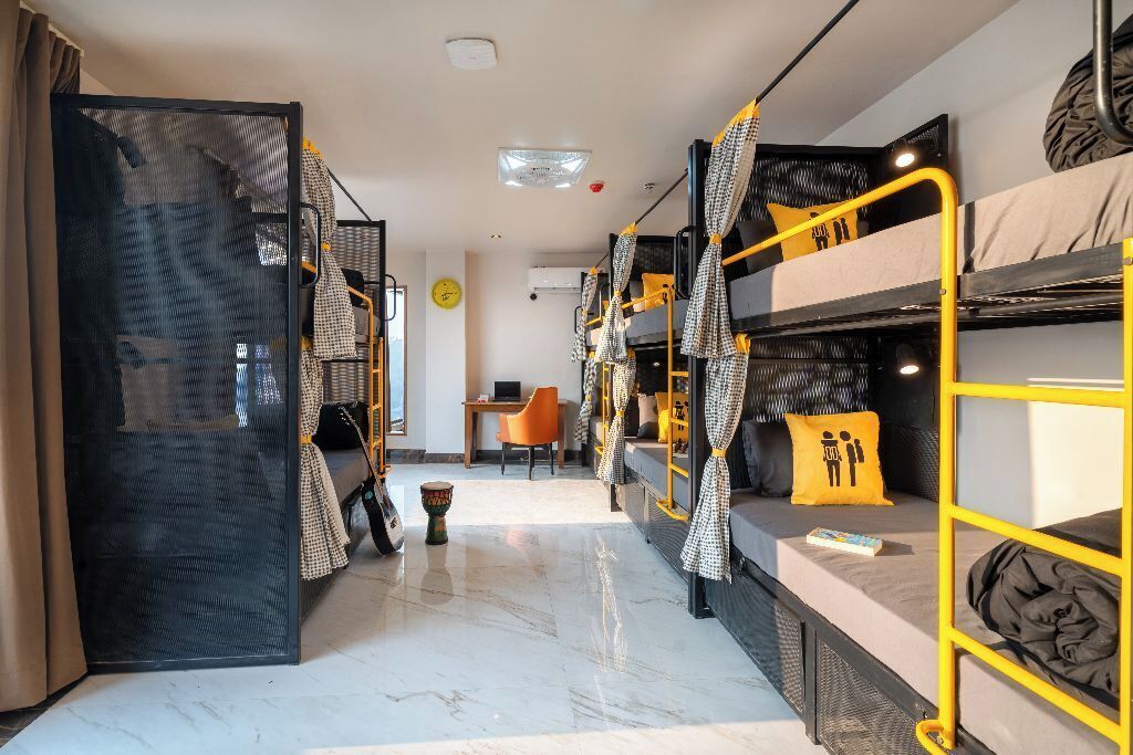 A dormitory room with bunk beds, a desk, and a chair.