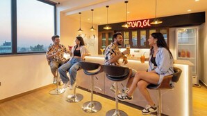 Eine moderne Bar mit vier Hockern, einem Neonlichtschild und einer Bar, die eine gekühlte Getränkeauslage bietet.