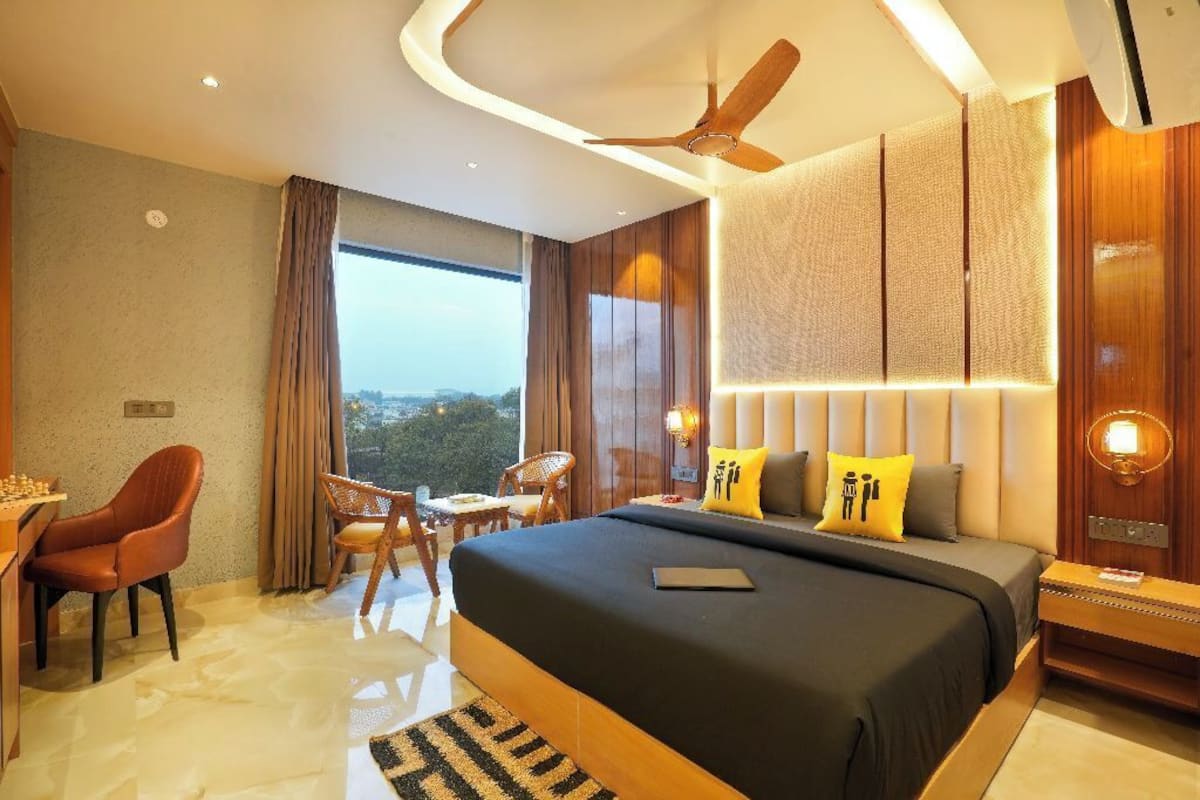 A modern hotel room with a large bed, a desk, and a view of the city.