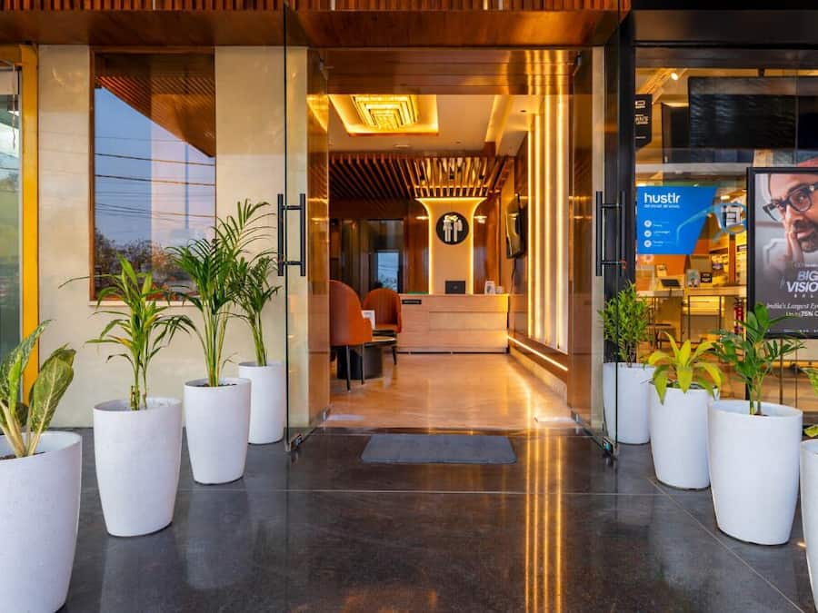 Een receptiehal van een hotel, modern ingericht, met een receptiebalie, een zithoek en potplanten.